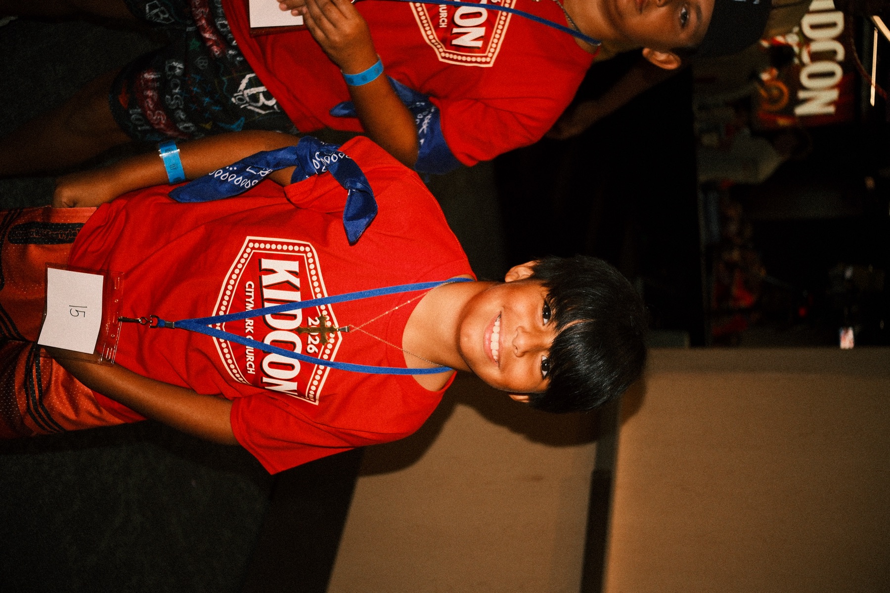 A camper smiling in his KidCon shirt and bandana
